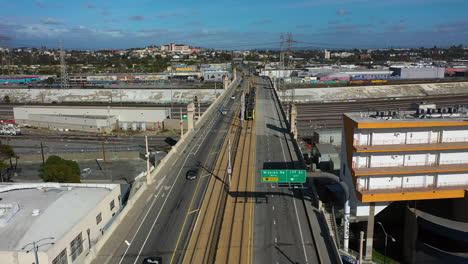 Toma-Aérea-Ascendente-Siguiendo-Un-Tranvía-Que-Se-Mueve-Sobre-El-Ferrocarril-En-Los-Ángeles,-EE.UU.