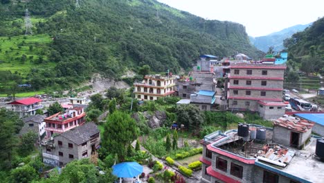 Atemberaubendes-Luftpanorama-Von-Gebäuden-Am-Ufer-Des-Gandaki-Flusses-Mit-Einem-Grünen-Berghintergrund-Im-Dorf-Marpha-In-Nepal