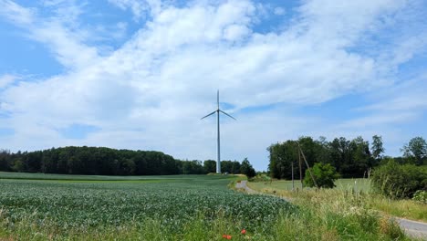 A-wind-turbine-is-tall-and-white,-standing-in-a-field-in-Sauerland