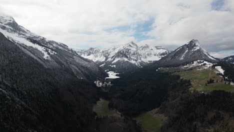 An-awe-inspiring-aerial-perspective-captures-the-grandeur-of-the-Swiss-Alps,-where-snow-crowned-peaks-are-shrouded-in-clouds-and-mist,-situated-near-Glarus,-Switzerland