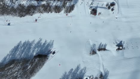 Top-down-tracking-shot-flying-down-mountain-following-ski-area,-high-angle-flying-sideways