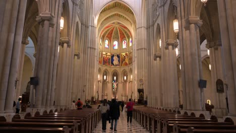 People-are-seen-inside-the-Roman-Catholic-Almudena-Cathedral,-completed-and-consecrated-in-1993-by-Pope-John-Paul-II,-as-arches,-columns,-and-pillars-decorate-and-support-the-ceiling-and-dome