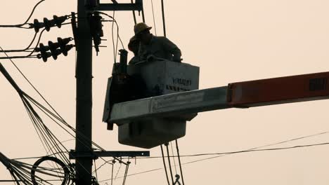 Reparadores-Eléctricos-Izados-En-Una-Grúa-Para-Llegar-A-Las-Partes-Afectadas-De-Un-Cable-Eléctrico-Y-Publicarlo-En-Un-Barrio-De-Bangkok,-Tailandia