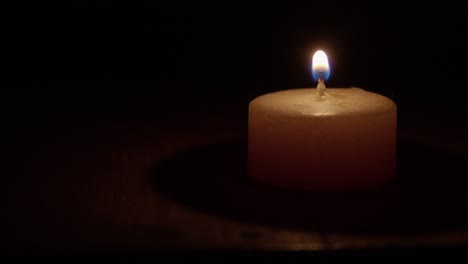 Closeup:-Golden-bees-wax-candle-it-lit-with-match-in-dark-black-room