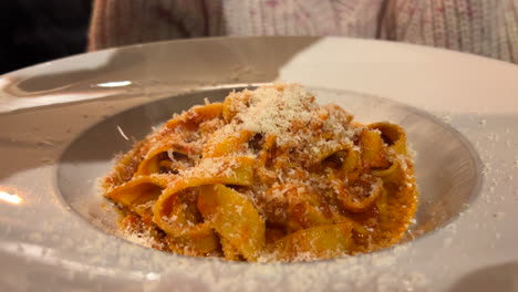 Ein-Kellner-Reibt-Parmesankäse-Auf-Bolognese-Tagliatelle-Nudeln-In-Einem-Restaurant,-Traditionelle-Italienische-Küche,-4k-Aufnahme