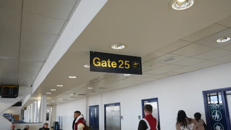 Terminal-25-Del-Aeropuerto,-Puerta-Veinticinco,-Cartel-En-Una-Concurrida-Sala-De-Espera-De-Embarque