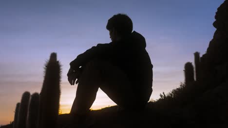 Silhouette-Eines-Traurigen-Teenagers,-Der-In-Der-Abenddämmerung-In-Bolivien-In-Der-Wüste-Sitzt