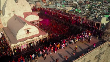 Aerial-drone-view-Many-people-are-going-to-have-darshan-inside-the-temple-and-many-people-are-playing-dhuleti-outside-and-many-people-are-pouring-water-and-color-from-the-top-of-the-temple