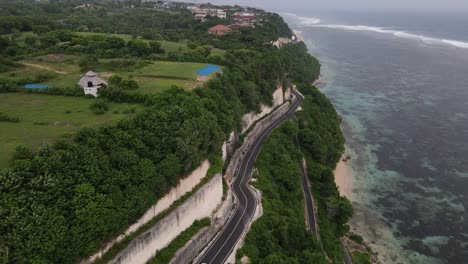 Aerial-view,-cliffside-asphalt-road-and-sea-located-on-Tanah-Barak-beach,-Bali-island,-Indonesia