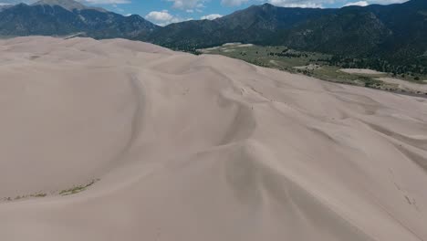 A-spectacular-high-flying,-landscape-drone-shot-over-the-Great-Sand-Dunes-of-Colorado,-home-to-the-tallest-sand-dunes-in-all-of-North-America,-with-the-Sangre-de-Cristo-Mountains-in-the-background