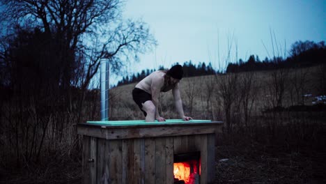 Hombre-Bañándose-En-Un-Jacuzzi-De-Leña-Diy-En-El-Paisaje-Natural