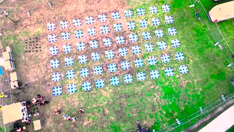 Drones-being-setup-and-ready-for-nighttime-display-by-technicians-at-Wine-Fair,-Aerial-top-view-descent-shot