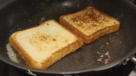 Thick-white-bread-slices-are-toasted,-turned-over-in-hot-buttered-pan