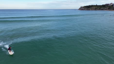 Toma-Aérea-De-Un-Dron-Siguiendo-A-Una-Surfista-De-Tabla-Larga-En-Bondi-Beach-En-Sydney