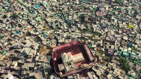 Vista-Aérea-De-Drones-Toma-De-ángulo-Superior-Donde-Muchas-Personas-Están-Jugando-Dhuleti-Y-Toda-La-Gente-Está-Mirando-A-La-Gente-Jugando-Dhuleti-Desde-Lo-Alto-Del-Templo,-Toma-Establecida-De-Uttar-Pradesh