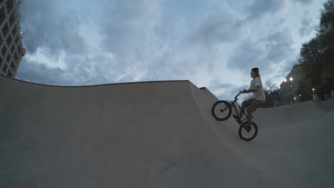 BMX-Biker-Springt-Gewaltig-Aus-Der-Skatepark-Bowl,-Quarterpipe-Hip,-Bike-Trick-Fliegt-In-Der-Abenddämmerung-In-Extremer-800-fps-Zeitlupe-Durch-Die-Luft,-4K-Fischauge