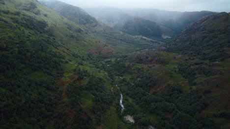 Aerial-foggy-drone-landscape-of-Fort-William-Valley,-Scotland-green-natural-environment-wet-valley-river-flow-through-green-forest