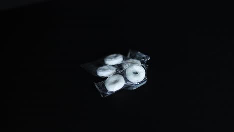 bright-white-breath-mints-laying-on-a-dark-black-background