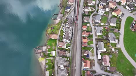 Drone-shot-bird's-eye-view-Unterterzen-Mols-Walensee-Churfirsten-from-above---trains-and-cars-driving-through-town