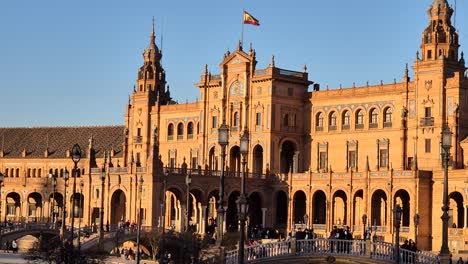 Plaza-De-España-Al-Atardecer-Con-La-Bandera-De-España-Ondeando-Al-Viento,-Sevilla,-España