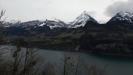 Drone-shot-of-snow-covered-mountains-under-cloudy-sky-in-Switzerland