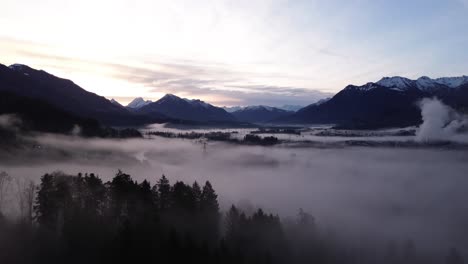 Drone-fly-towards-Sunrise,-Aerial-Drone-View-of-Misty-Winter-Mountain-Landscape-with-snow-covered-summits-in-Austria