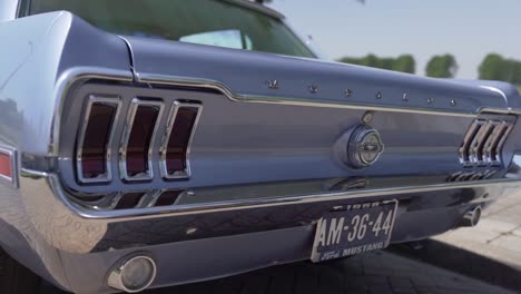 Slowmotion-Nahaufnahme-Mit-Schwenkansicht-Des-Hecks-Eines-Blauen-Ford-Mustang-An-Einem-Sonnigen-Tag