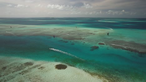 Cayo-vapor-with-kite-surfers-and-turquoise-waters,-sunny-day,-aerial-view