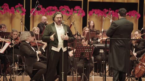 male-opera-singer-on-stage-with-orchestra-symphonic-band,-ensemble-performing-Italian-opera-at-sun-yet-sen-Memorial-Hall