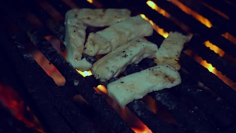 Fingers-of-herb-spiced-Halloumi-cheese-fry-on-open-fire-grill-at-night