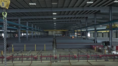 Piles-of-steel-beams-organized-in-warehouse-with-overhead-bridge-crane