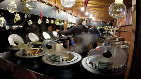 Woman-cooking-dinners-and-orders-on-Christmas-stalls-with-food-at-night-on-the-Main-Market-Square-in-Krakow,-Poland