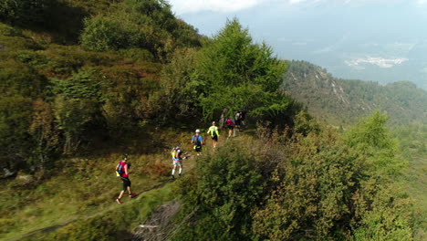 Aerial-drone-shot-of-a-group-of-professional-mountain-trekkers-running-on-mountain-trail