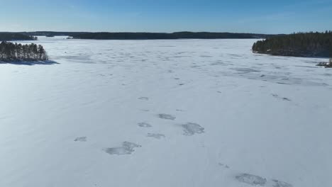 Flying-over-a-frozen-lake-and-islands-covered-in-trees