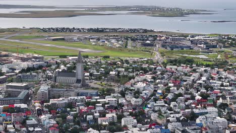 Aerial-View-of-Downtown-Reykjavik,-Iceland-on-Sunny-Day,-Central-Church,-Buildings-and-Old-Airport