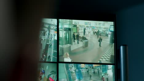 Monitoring-multiple-CCTV-screens-showing-busy-station-activity,-people-walking,-security-theme,-urban-environment