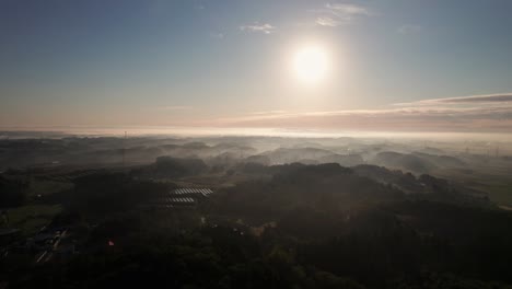 Aerial-slow-motion-sunrise-landscape-in-japanese-countryside-village-mountain-range-background-in-green-outskirts-environment,-japan-asia-during-summer,-golden-sun-shining-on-top