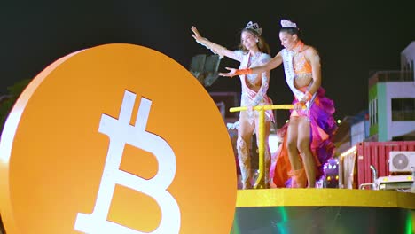 Criptomoneda-Naranja-Bitcoin-Con-Una-Hermosa-Mujer-Caucásica-Bailando-Encima-De-Una-Carroza-Del-Desfile-Por-La-Noche