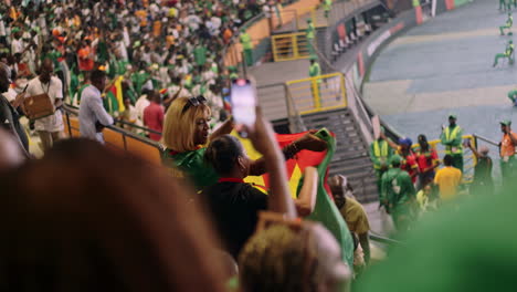 Dos-Mujeres-Bailando-Y-Ondeando-La-Bandera-De-Camerún-En-Las-Gradas