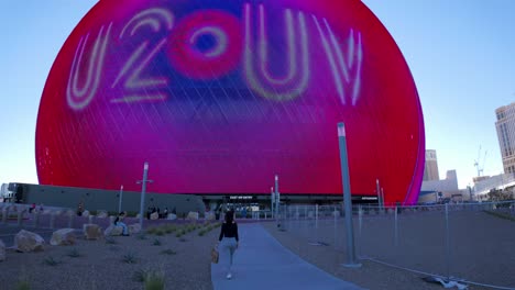 Female-tourist-walks-toward-Sphere-Las-Vegas-concert-venue-with-LED-display-on-exterior