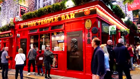 Iconic-red-facade-of-the-Temple-Bar-Pub-with-people-enjoying-the-nighttime