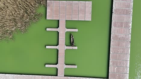 Ascending-shot-of-fishing-platform-on-stilts-by-a-lake-in-northern-Greece-|-Top-down-shot-of-a-fishing-platform-in-murky-green-water