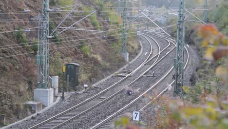 Red-Deutsche-Bahn-train-approaching-on-tracks-surrounded-by-autumn-foliage