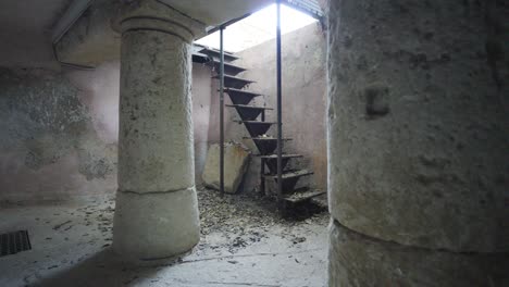 Slow-revealing-shot-of-a-metal-ladder-leading-to-antique-stone-pillars