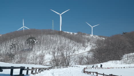 Tourist-at-Walk-Trail-with-Wooden-Fence-in-Winter-Daegwallyeong-Sky-Ranch---wide-angle