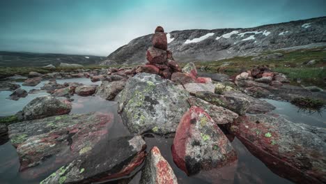Peculiar-stone-cairns-stand-on-lichen-covered-rocks-and-are-surrounded-by-puddles-of-meltwater
