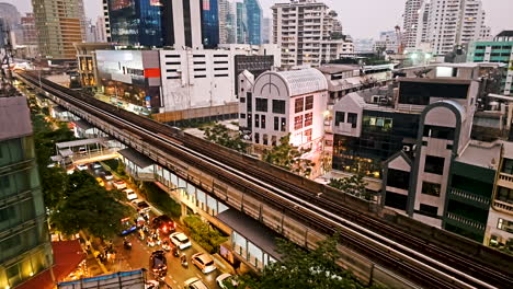 Zeitraffer-Einer-Pulsierenden-Kosmopolitischen-Stadt,-Der-Die-Verschiedenen-Gebäude-Im-Zentrum-Des-Geschäftszentrums-Und-Den-Skytrain-Zeigt,-Der-Durch-Die-Hauptverkehrsstraße-In-Bangkok,-Thailand-Fährt