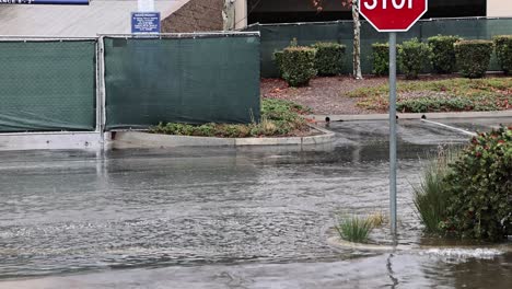 Weiße-Limousine-Fährt-Während-Eines-Regenschauers-Schnell-Durch-Eine-überflutete-Straße-In-San-Bernardino,-Kalifornien,-An-Einem-Stoppschild,-60 fps