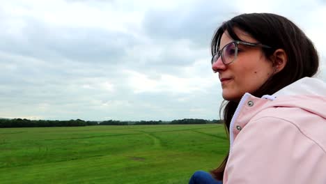 Young-woman-with-glasses-looking-at-a-vast-field-of-green-grass-in-Phoenix-Park,-Dublin