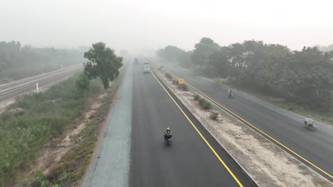 Drohne-Fliegt-Hinter-Motorradfahrer-über-Sahiwal-Zur-Multan-Road-In-Punjab,-Es-Ist-Sehr-Neblig